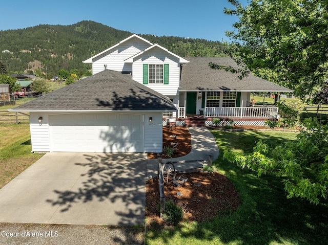 5904 N 15th St, Dalton Gardens, ID 83815 - tri-level home featuring covered porch, a mountain view, a shingled roof, driveway, and an attached garage