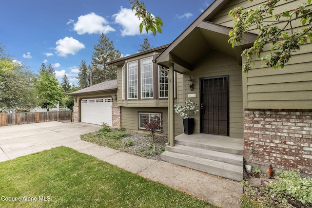 405 W 22nd Ave, Post Falls, ID 83854 - view of exterior entry featuring concrete driveway, an attached garage, fence, and brick siding
