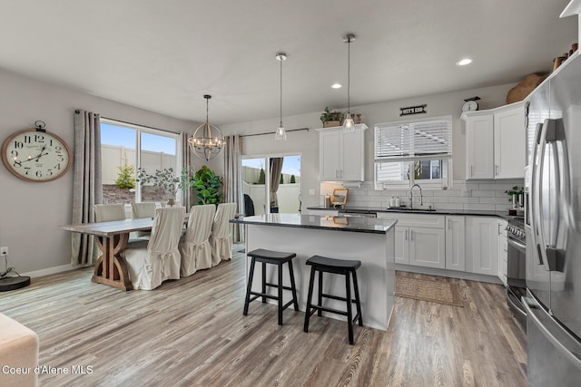 5441 W Gumwood Cir, Post Falls, ID 83854 - kitchen with decorative backsplash, light wood-style flooring, dark countertops, appliances with stainless steel finishes, and a center island
