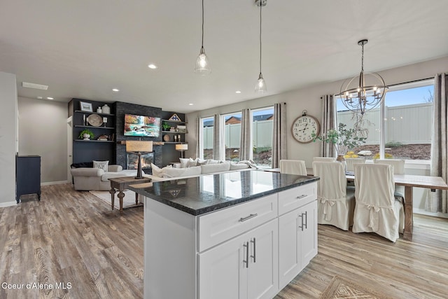 5441 W Gumwood Cir, Post Falls, ID 83854 - kitchen featuring white cabinets, light wood finished floors, a center island, decorative light fixtures, and an inviting chandelier