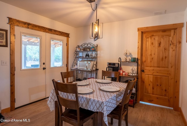 dining space featuring baseboards, light wood finished floors, and visible vents