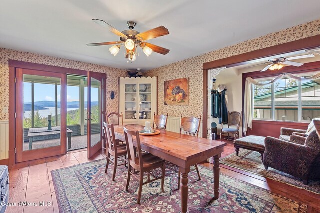 3467 E Sunset Dr, Harrison, ID 83833 - dining space with wallpapered walls, a ceiling fan, light wood-type flooring, and healthy amount of natural light