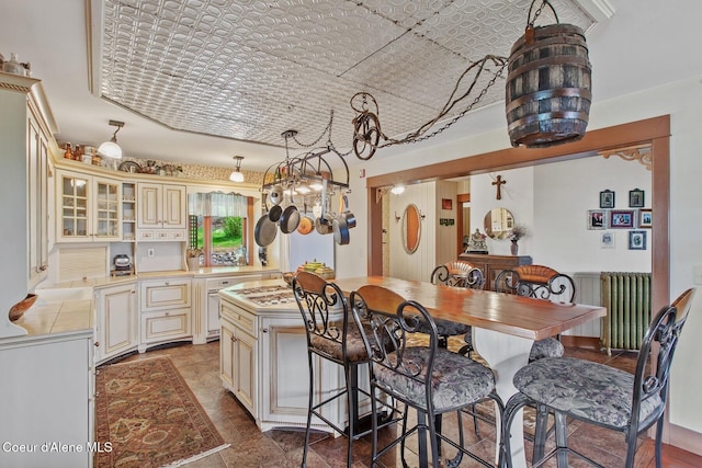 3467 E Sunset Dr, Harrison, ID 83833 - kitchen featuring cream cabinetry, a center island, a breakfast bar area, radiator, and tile countertops