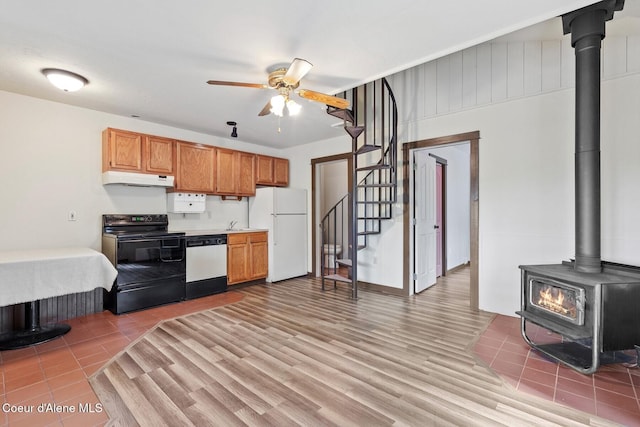 3467 E Sunset Dr, Harrison, ID 83833 - kitchen with black electric range oven, freestanding refrigerator, dishwasher, a wood stove, and under cabinet range hood