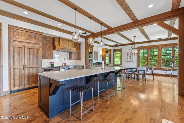 4669 S Arrow Point Dr # 210, Harrison, ID 83833 - kitchen with beamed ceiling, a kitchen bar, tasteful backsplash, light wood-type flooring, and a large island with sink