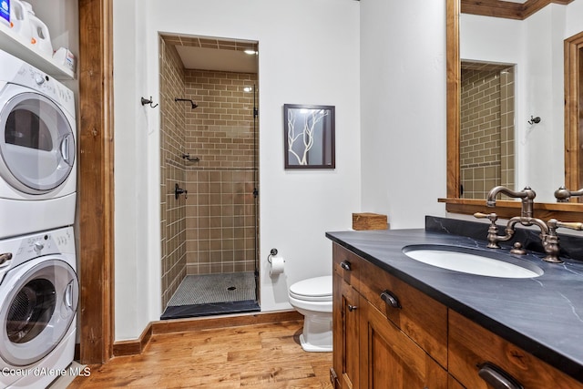 4669 S Arrow Point Dr # 210, Harrison, ID 83833 - bathroom featuring stacked washer / dryer, toilet, tiled shower, and wood finished floors