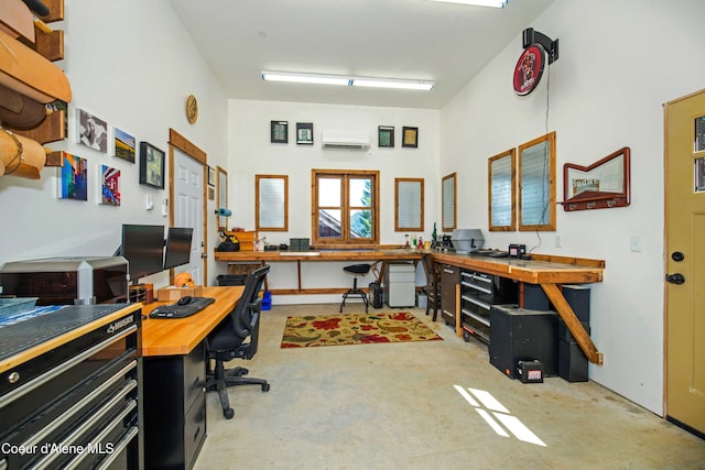 office space with a wall mounted AC, unfinished concrete floors, and a workshop area