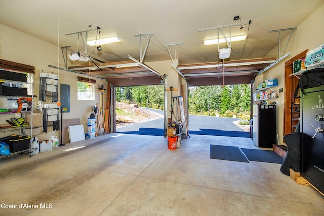 garage with electric panel, a garage door opener, and freestanding refrigerator
