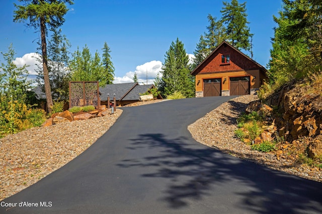 view of front of house with stone siding, a detached garage, and an outdoor structure