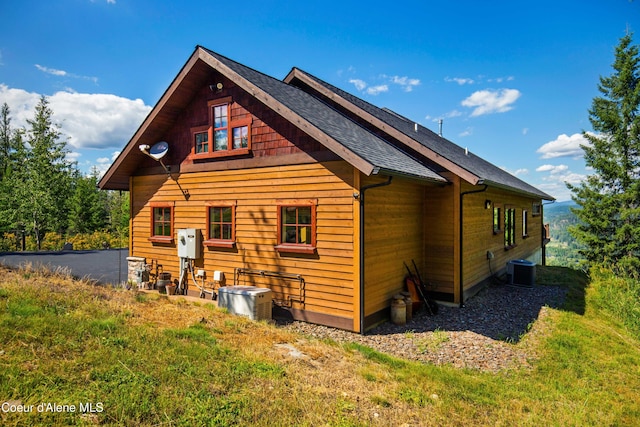 back of property with cooling unit and a shingled roof