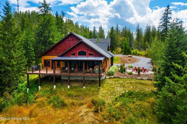 back of house featuring a lawn and a wooded view