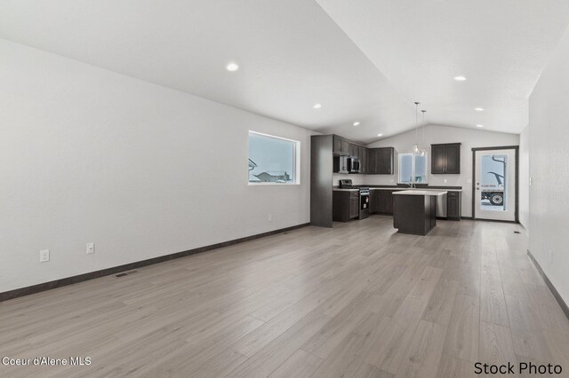 11669 N Railway Ave, Rathdrum, ID 83858 - kitchen with stainless steel appliances, lofted ceiling, open floor plan, a center island with sink, and light wood finished floors