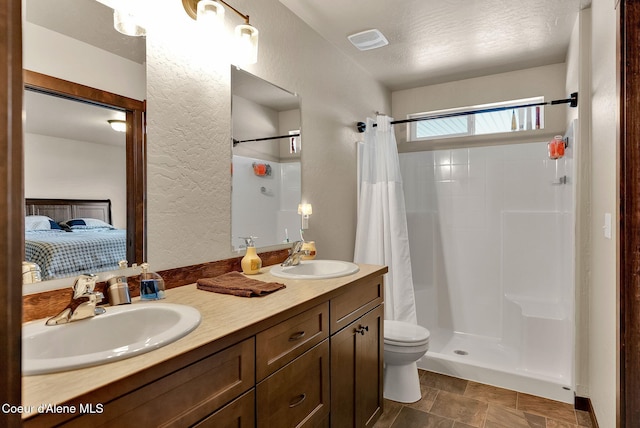 12379 N Cavanaugh Dr, Rathdrum, ID 83858 - ensuite bathroom featuring a shower with curtain, double vanity, toilet, and a textured wall