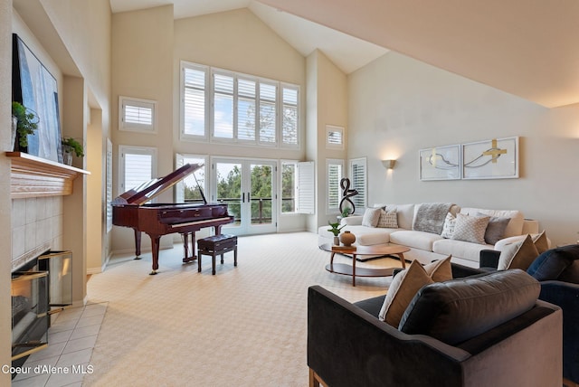 living area featuring high vaulted ceiling, baseboards, a tiled fireplace, french doors, and light colored carpet