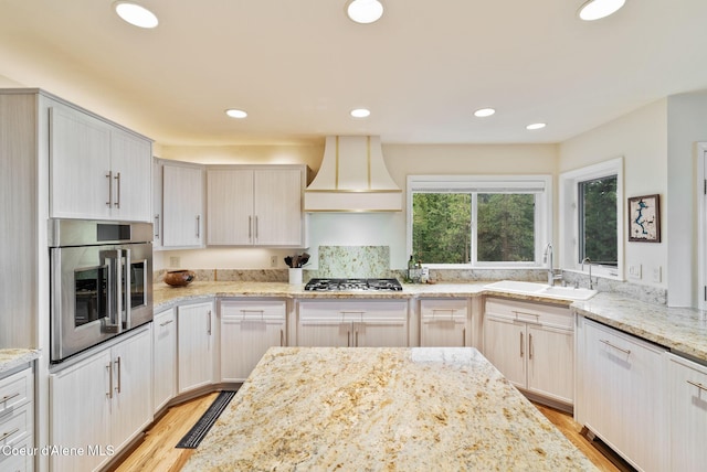 kitchen with light wood-style flooring, stainless steel appliances, recessed lighting, a sink, and custom range hood