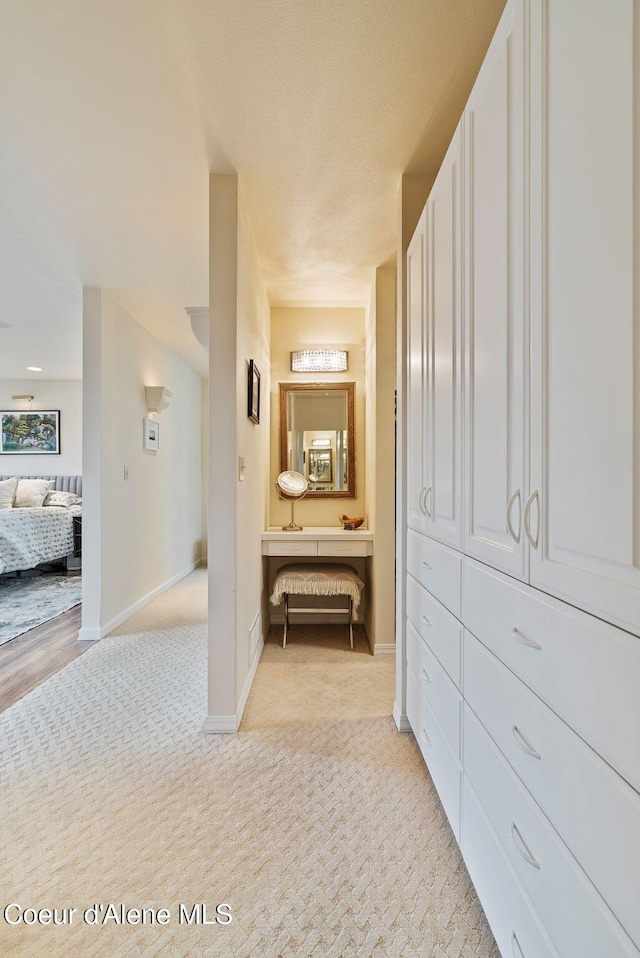 hallway featuring baseboards and light colored carpet