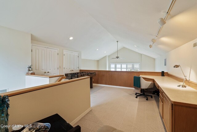 unfurnished office featuring a wainscoted wall, wood walls, lofted ceiling, light colored carpet, and track lighting