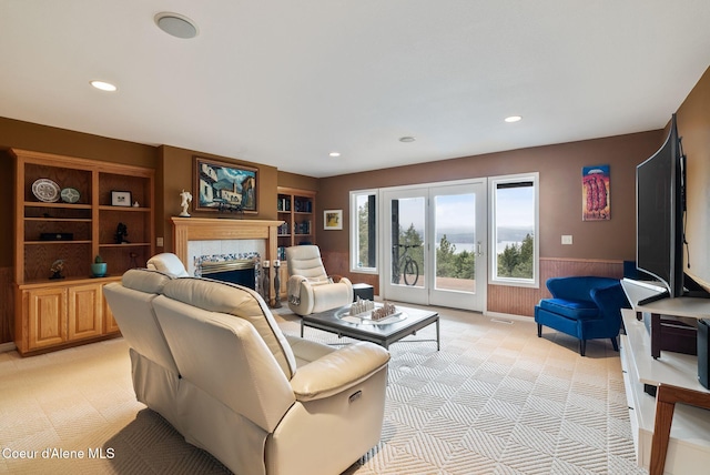 living room featuring recessed lighting, light carpet, a fireplace, and wainscoting