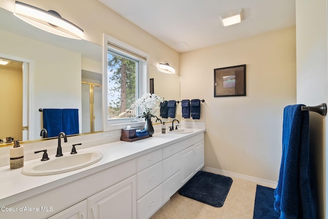 bathroom with a shower stall, baseboards, double vanity, and a sink