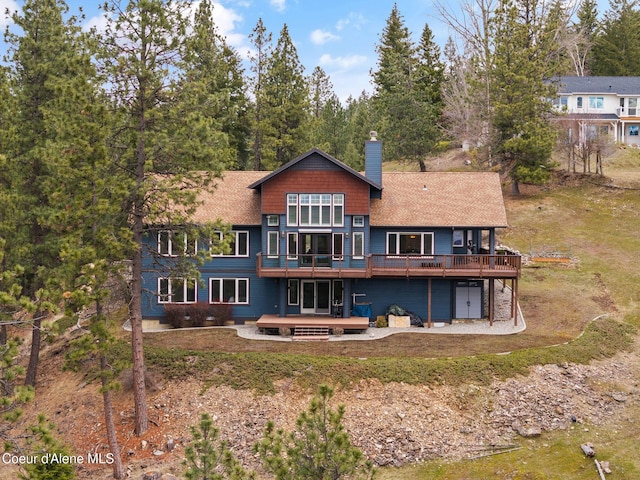 back of property with a chimney and a wooden deck
