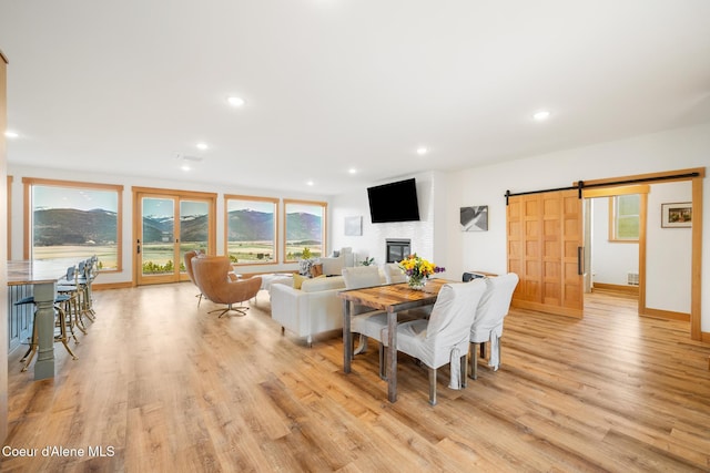 dining area with recessed lighting, light wood-type flooring, baseboards, a barn door, and a fireplace