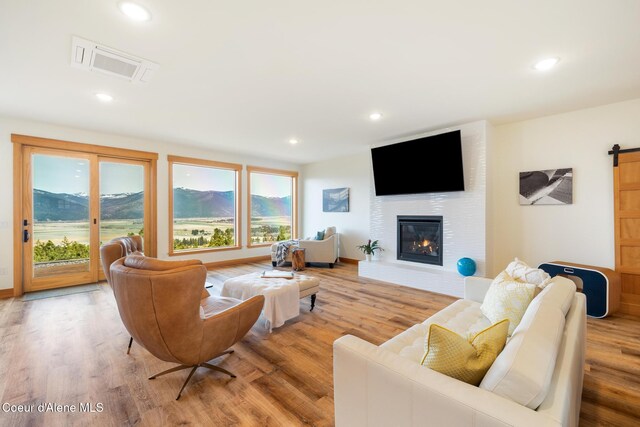 living room featuring plenty of natural light, visible vents, a barn door, and light wood-type flooring