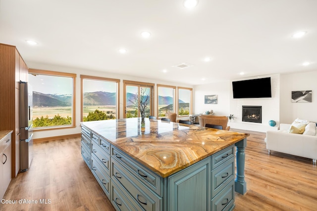 kitchen with light wood-style flooring, visible vents, a glass covered fireplace, and recessed lighting