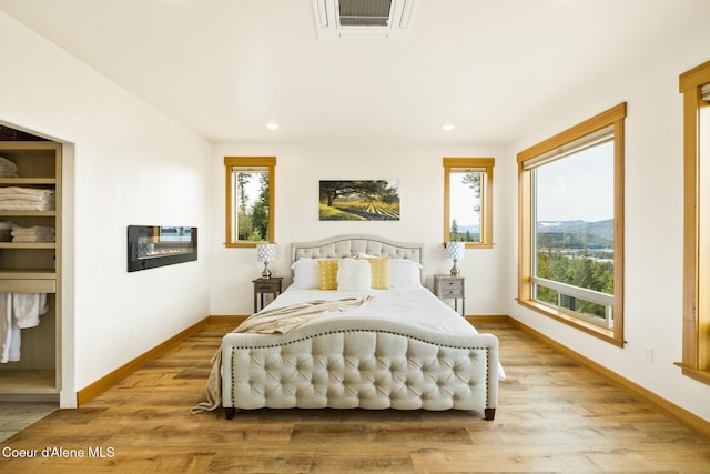 bedroom with baseboards, visible vents, wood finished floors, and recessed lighting