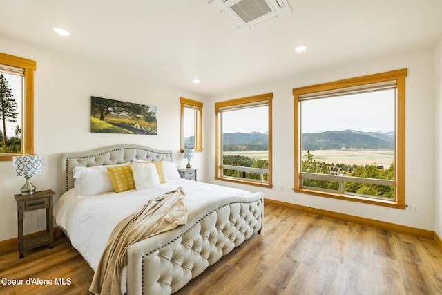bedroom with multiple windows, visible vents, wood finished floors, and a mountain view