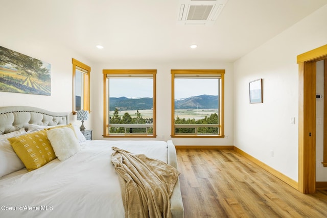 bedroom with a mountain view, light wood-style flooring, baseboards, visible vents, and recessed lighting