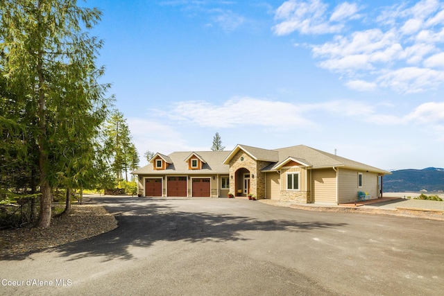 view of front of property with stone siding, aphalt driveway, a shingled roof, and an attached garage