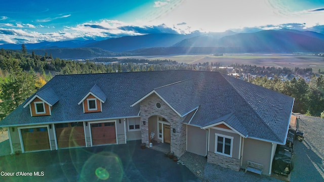 view of front of house with stucco siding, stone siding, a mountain view, and aphalt driveway