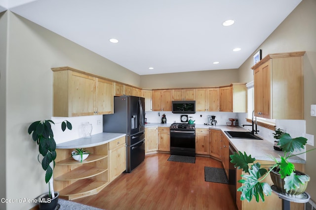 kitchen with light countertops, black fridge with ice dispenser, gas range, light brown cabinetry, and a sink