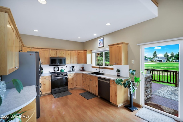 kitchen featuring light countertops, a sink, stainless steel appliances, and light wood finished floors