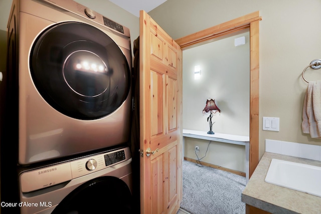 laundry area with carpet flooring, a sink, baseboards, and stacked washing maching and dryer