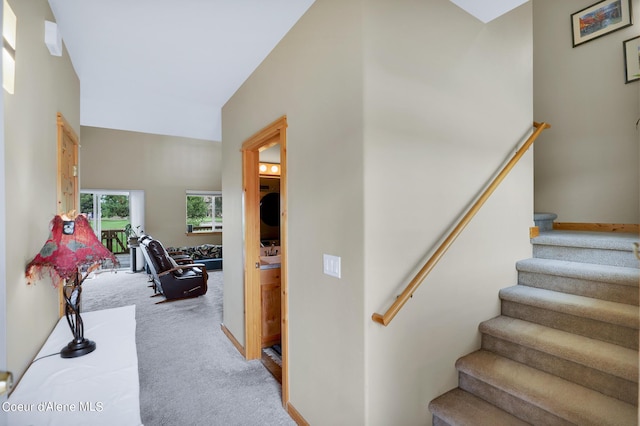 stairs with baseboards, high vaulted ceiling, and carpet
