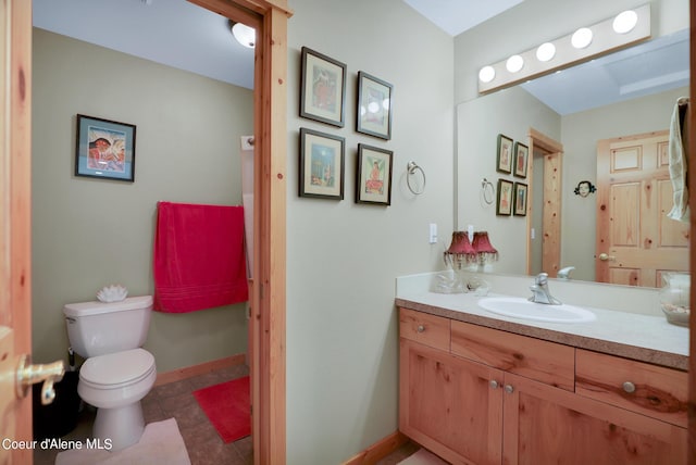 bathroom featuring toilet, vanity, tile patterned floors, and baseboards
