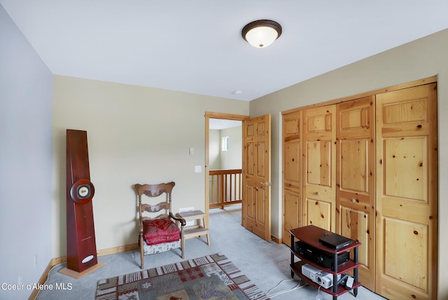 sitting room featuring baseboards and light carpet