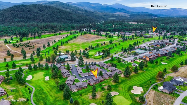 drone / aerial view with golf course view, a wooded view, and a mountain view