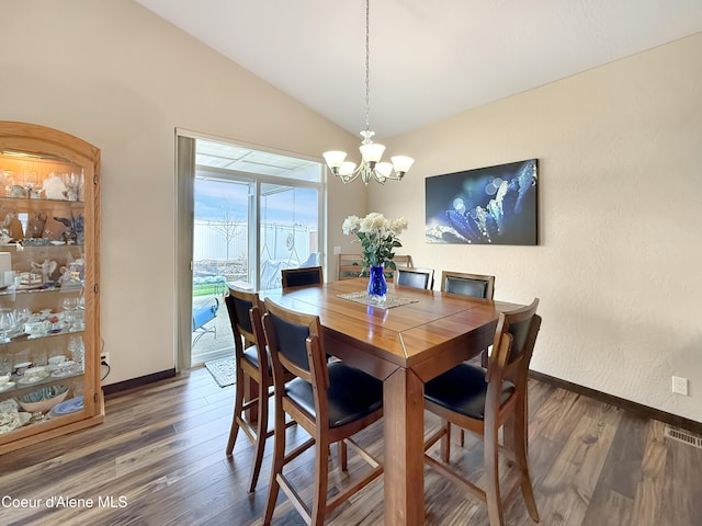 dining area featuring vaulted ceiling, a chandelier, wood finished floors, baseboards, and visible vents