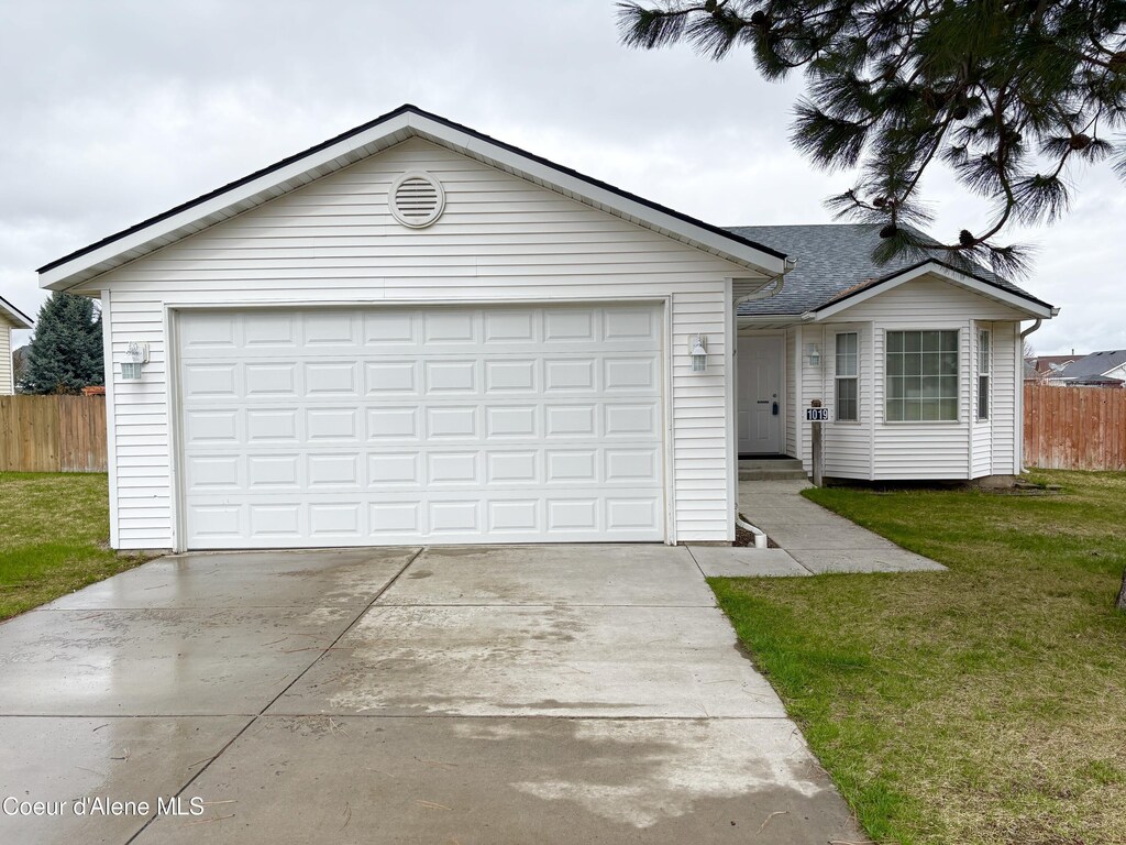 single story home with a front lawn, driveway, an attached garage, and fence
