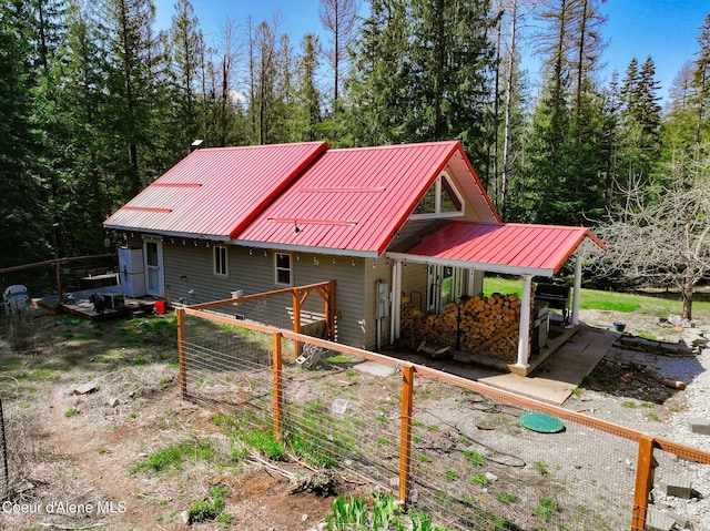 rear view of house with metal roof and fence