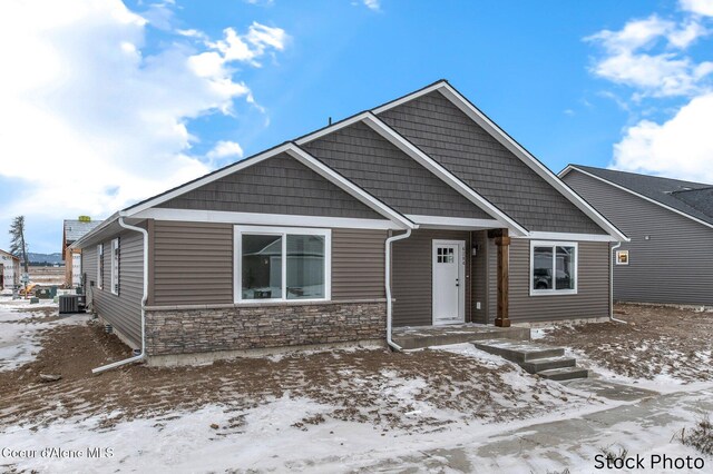 view of front facade featuring stone siding and central AC unit