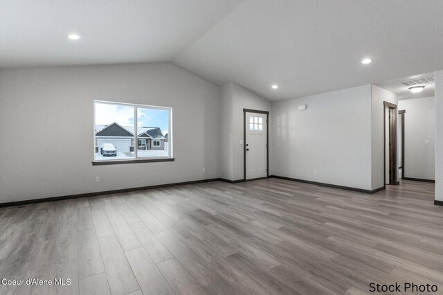 interior space with wood finished floors, plenty of natural light, vaulted ceiling, and visible vents