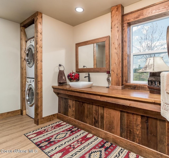 488 Fawn Ln, Bonners Ferry, ID 83805 - clothes washing area featuring a sink, light wood-style flooring, baseboards, stacked washer and clothes dryer, and laundry area