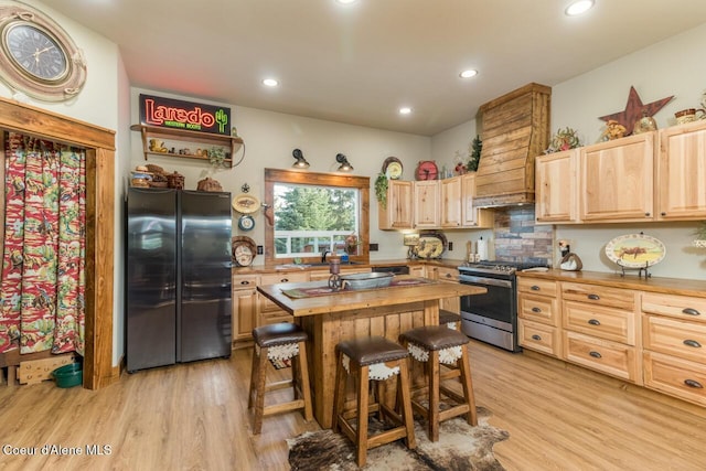488 Fawn Ln, Bonners Ferry, ID 83805 - kitchen with stainless steel appliances, light wood-style flooring, a kitchen bar, light brown cabinets, and wood counters