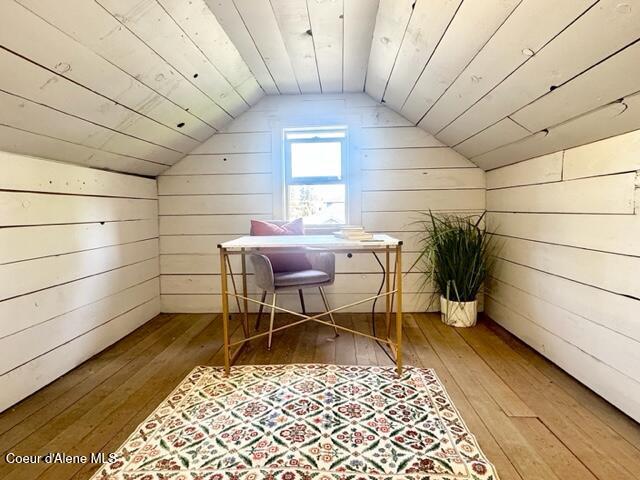 additional living space featuring hardwood / wood-style flooring, vaulted ceiling, and wooden walls