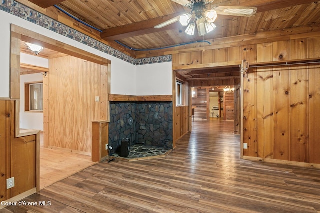unfurnished living room featuring wooden walls, wood finished floors, wood ceiling, and a ceiling fan