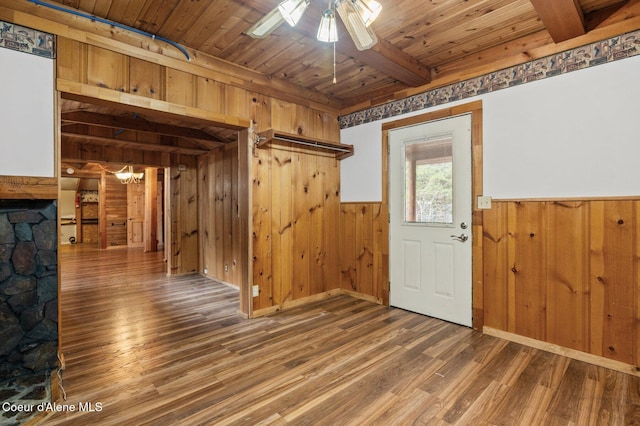 interior space featuring wood finished floors, wooden ceiling, beamed ceiling, and wooden walls