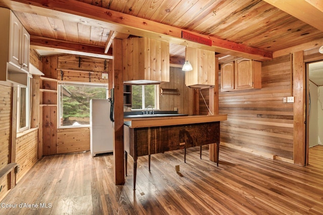 kitchen featuring hardwood / wood-style flooring, wood walls, a sink, and beam ceiling